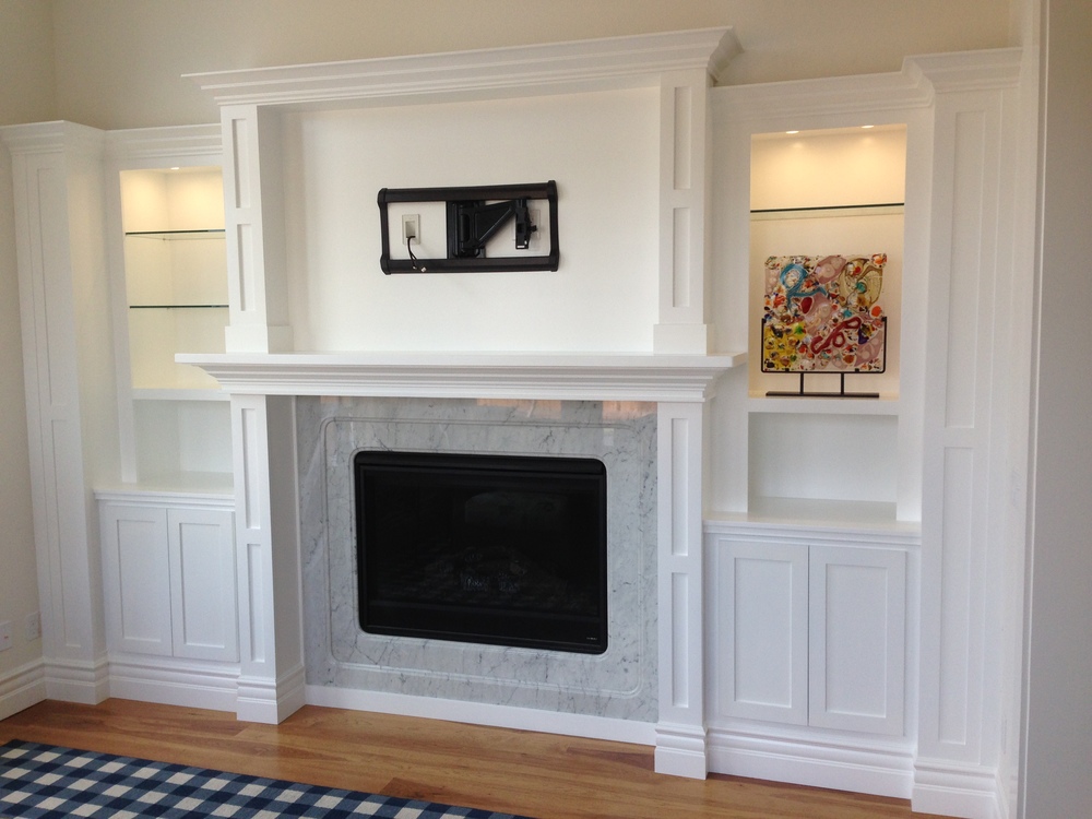 Custom wall unit with lighting, glass shelves, TV cutout and fireplace