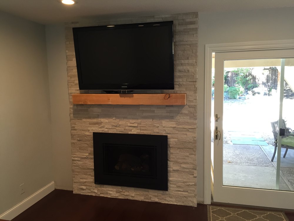 Stone TV wall with floating wood mantel